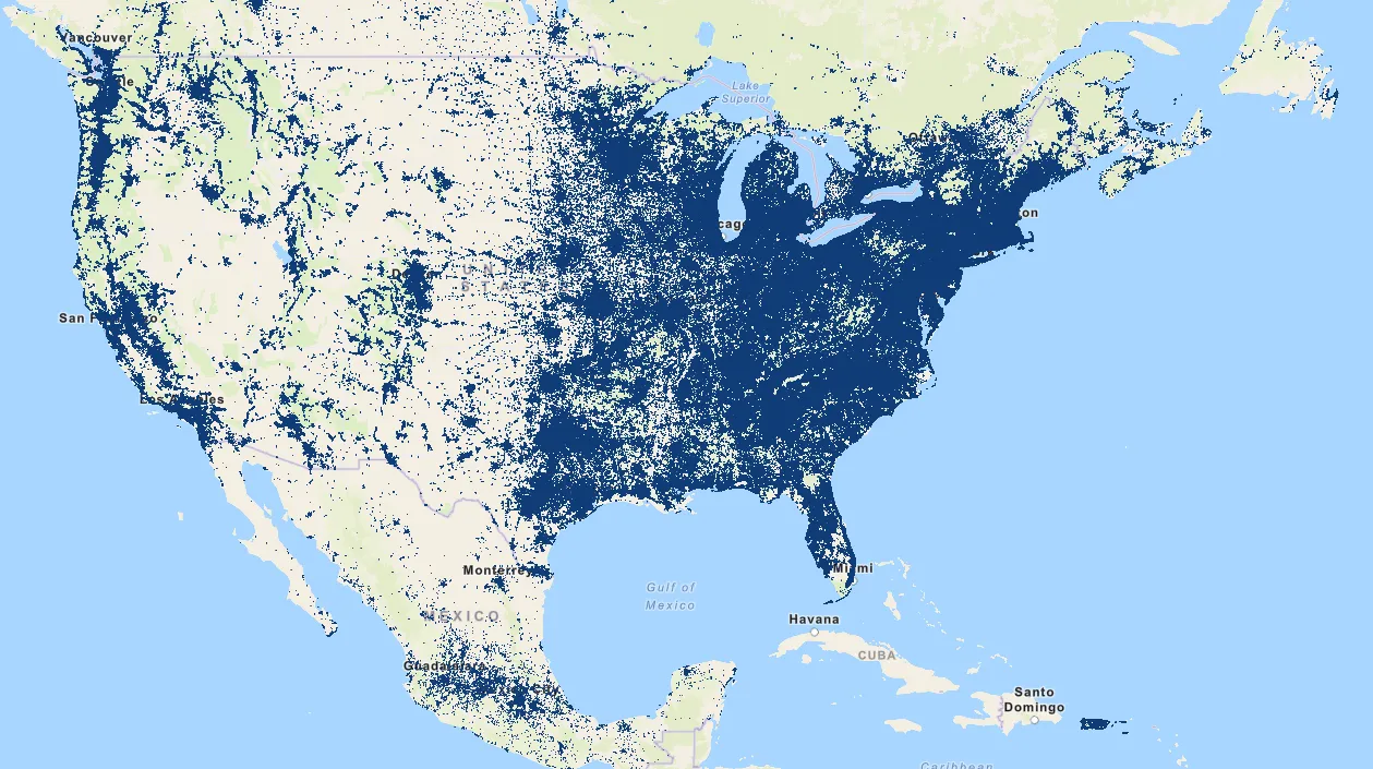 Amazon's official Sidewalk coverage map for the continental US, southern Canada, and northern Mexico. Areas where Sidewalk bridges are deployed are shown in dark navy blue against a pale beige basemap; uncovered areas remain pale. Dense navy fills the Northeast Corridor solidly from Boston down through New York, Philadelphia, DC, and Baltimore; another dense band runs through Chicago and the upper Midwest into Ohio and Michigan; the Southeast from Atlanta down through Florida is heavily filled; the Texas triangle Dallas-Houston-Austin-San Antonio is solid; California shows two heavy clusters at the Bay Area and LA basin, plus Seattle and Portland in the Pacific Northwest. In contrast, most of Montana, Wyoming, Nevada, western Texas, the Dakotas, large stretches of the Great Plains, and most of northern Canada are nearly empty of coverage. The map tells the population vs land story in one image — almost every populated metro is covered, almost no rural area is.