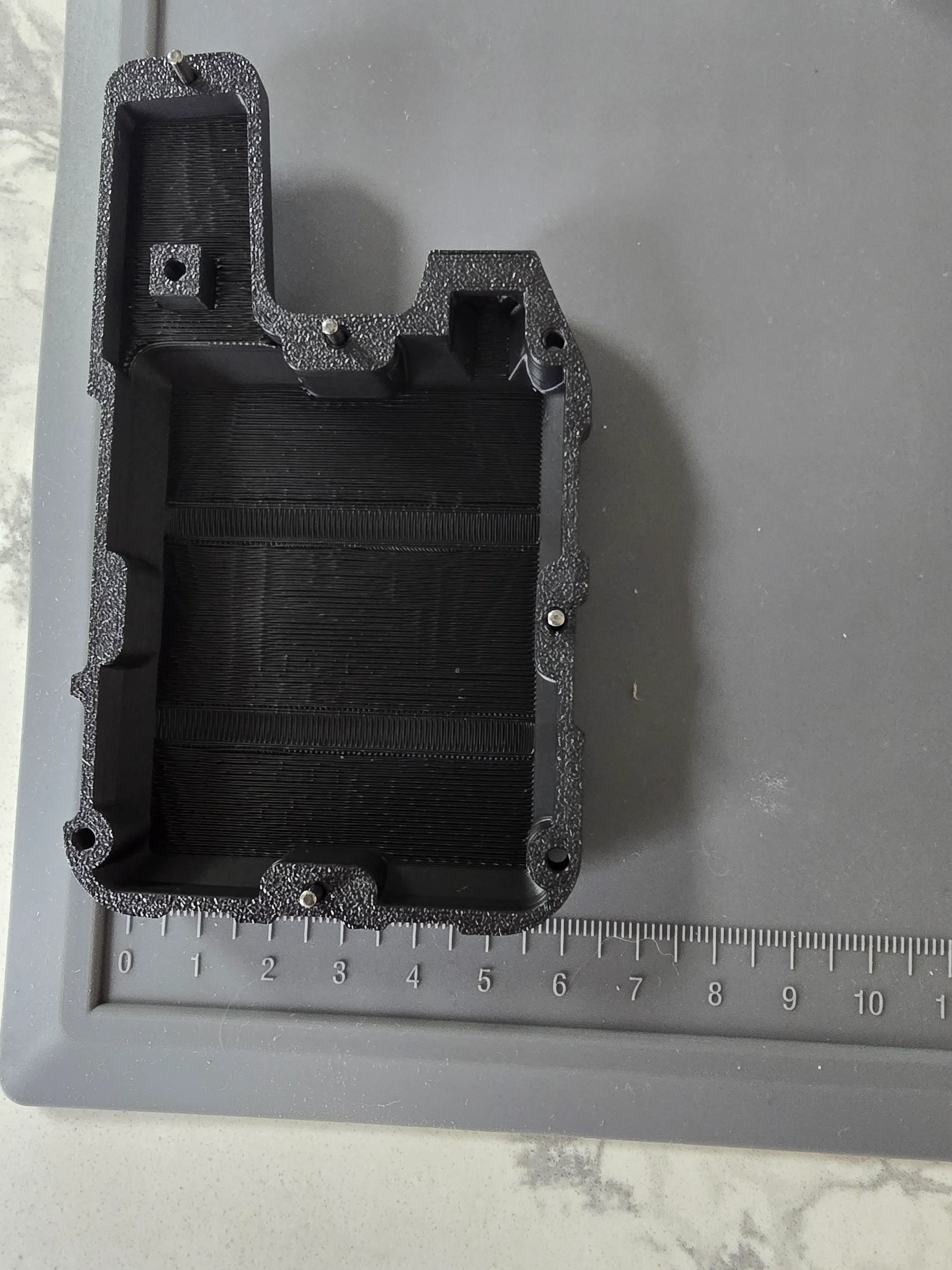 The other half of the enclosure with a ruler for scale, about 6 cm across — a reminder that this unit is the handheld base station, not the wearable collar.