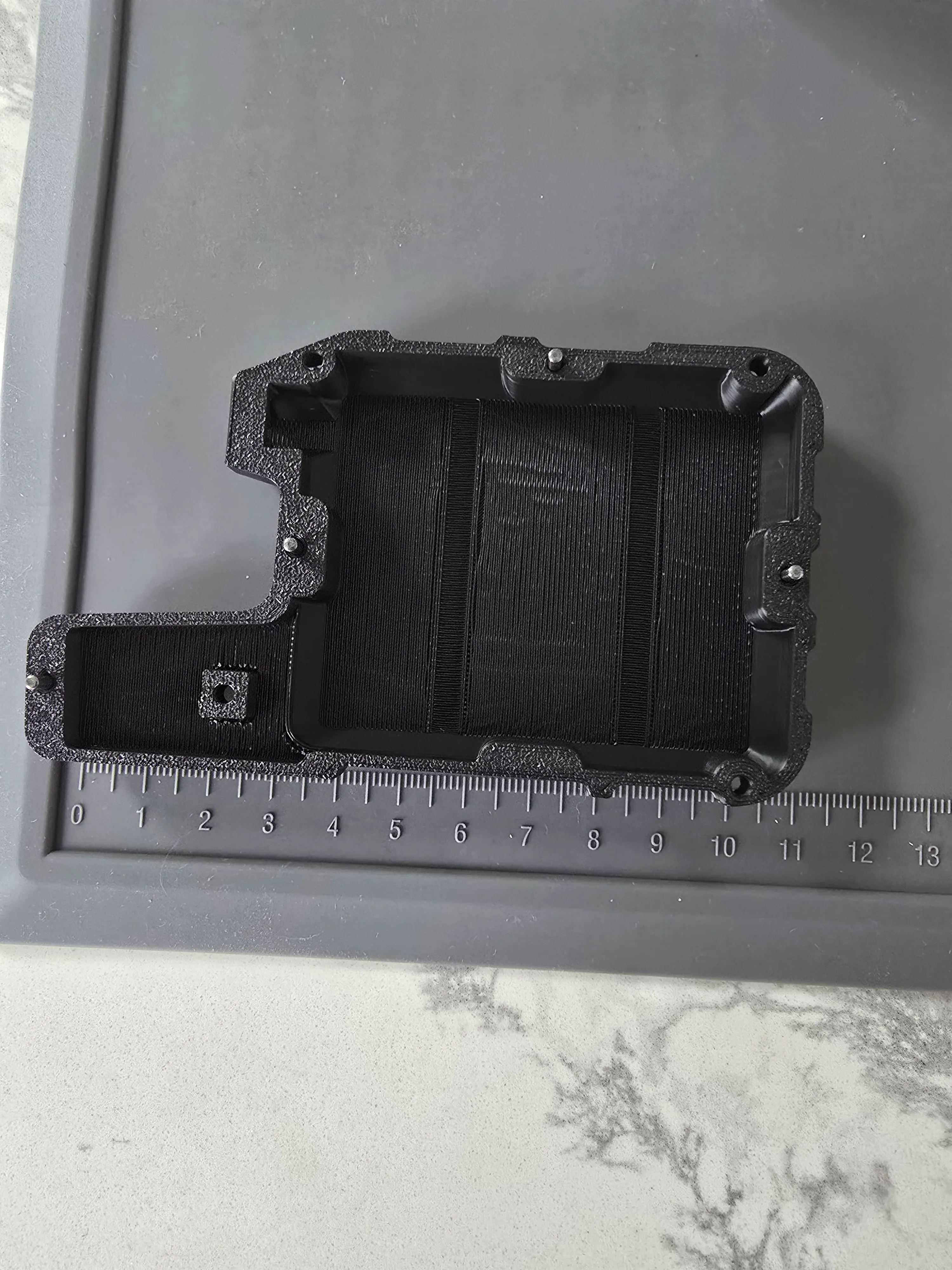 The Wio Tracker L1 enclosure against a centimeter ruler — roughly 10 cm tall, clearly handheld-sized rather than collar-sized.